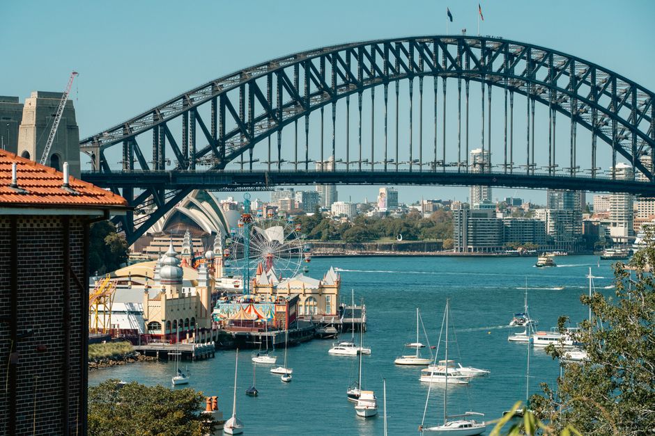 australia — A vibrant view of Sydney Harbour Bridge with Luna Park and sailboats highlighting the iconic skyline