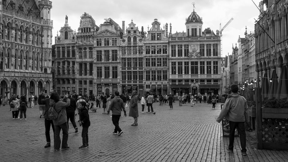 belgium — Black and white photo of Grand Place in Brussels with people strolling and historic architecture.