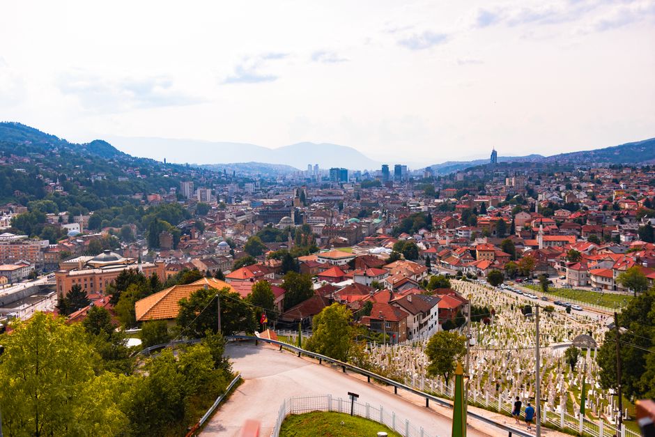 bosnia — Aerial view of Sarajevo, showcasing cityscape, red rooftops, and distant mountains.