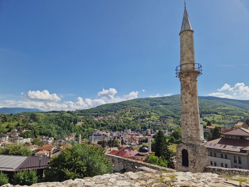 bosnia — A beautiful scenic view of a Bosnian town featuring a prominent mosque minaret against a clear blue 