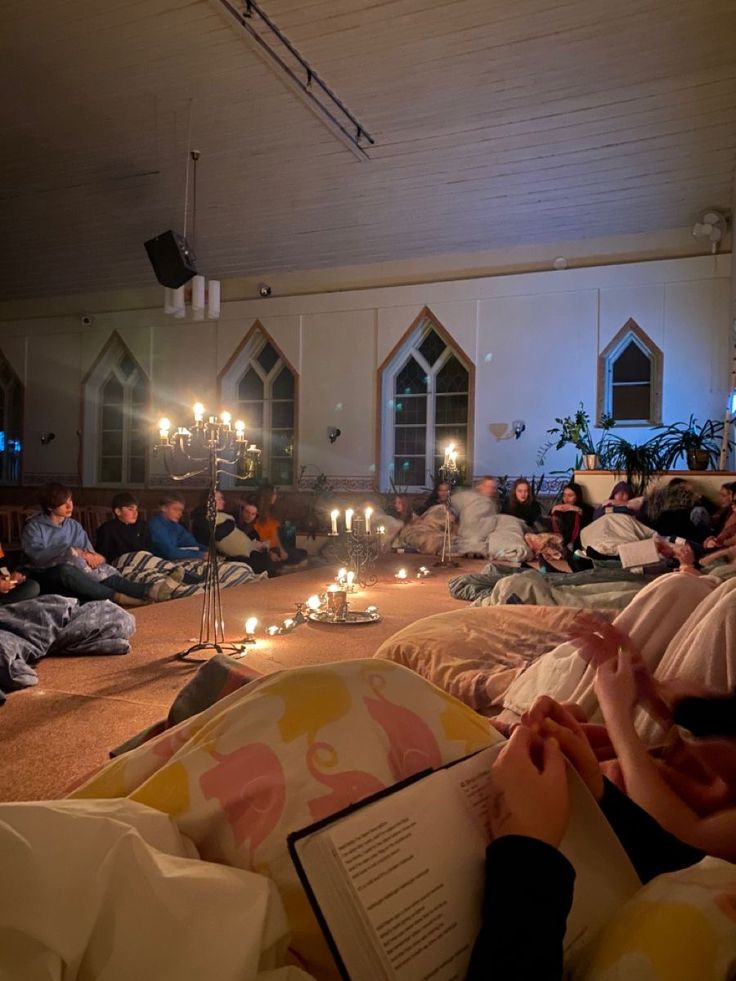 Campers gathered in sleeping bags around candlelight for an evening worship session