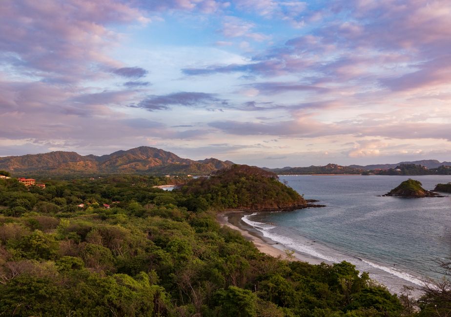 costa rica — A stunning aerial view of the Guanacaste coastline at sunset with lush greenery and gentle waves.