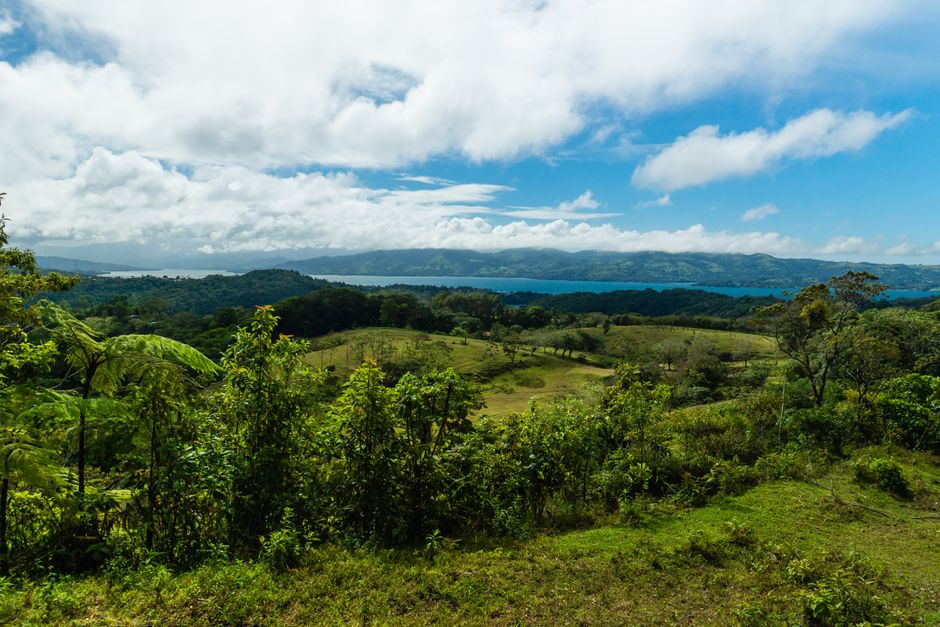 costa rica — Breathtaking landscape of lush green hills with a serene lake under a vibrant blue sky.