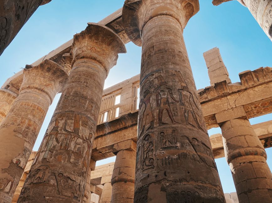 egypt — Impressive ancient Egyptian temple columns with hieroglyphics under a clear blue sky.
