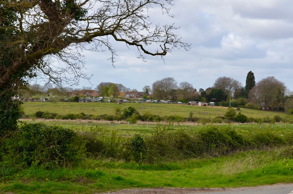 england — An idyllic countryside landscape showcasing lush green fields, trees, and a small village in the dis
