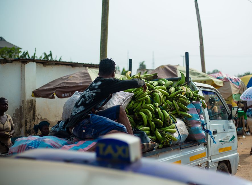 ghana — A vibrant street scene in Accra with a truck loaded with plantains and visible market activities.