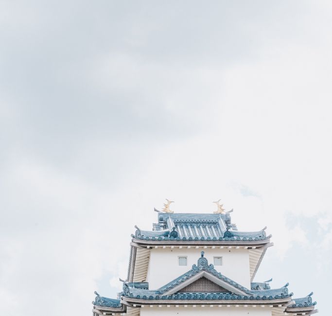 Elegant view of a traditional Japanese castle rooftop against a bright sky.
