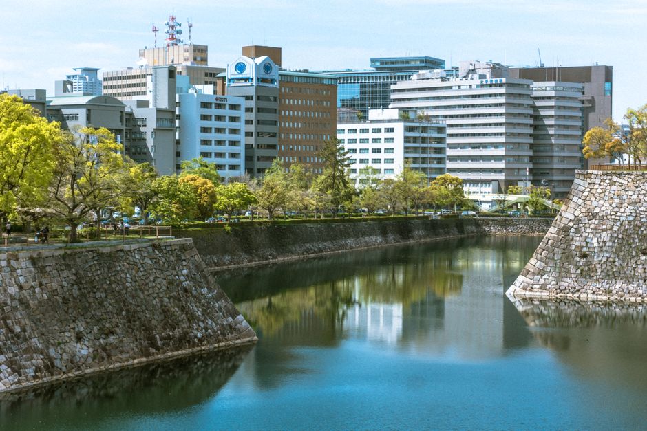 japan — City skyline reflected in a moat surrounded by greenery. Featured in the modern Japanese cityscape.