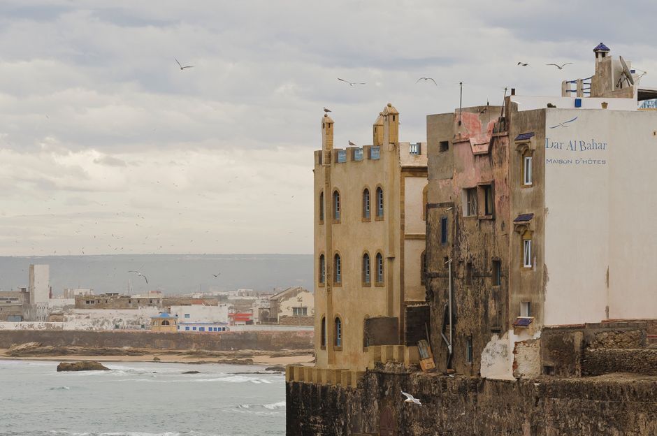 Exterior of aged shabby residential buildings located on embankment over wavy ocean against cloudy sky in Essa