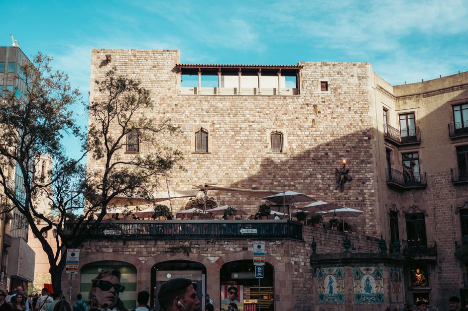 spain — Sunlit historic stone building in Barcelona's urban plaza captured during a bright day.