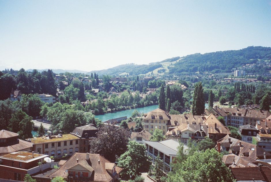 A scenic aerial view of a quaint Swiss town with lush greenery and a winding river.