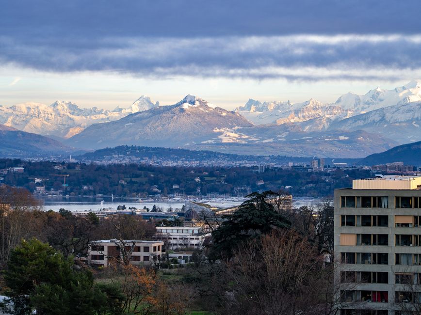 switzerland — A breathtaking view of Geneva with Swiss Alps backdrop under a cloudy sky at day.