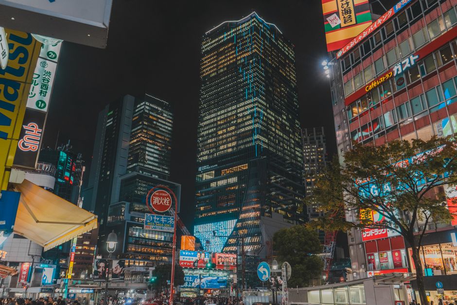 Night scene of Tokyo with illuminated skyscrapers and bustling street life, showcasing vibrant city energy.