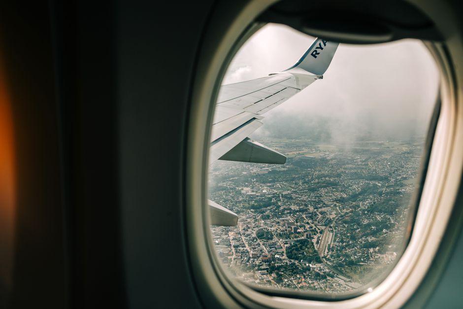 Scenic view of city from airplane window with wing visible, perfect for travel themes.