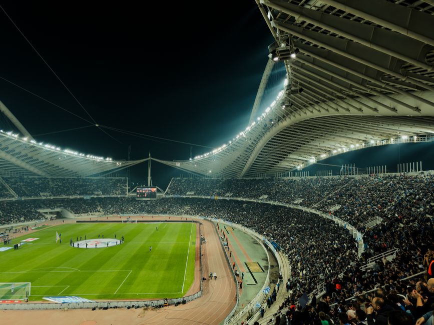 A packed football stadium under floodlights during a night match.